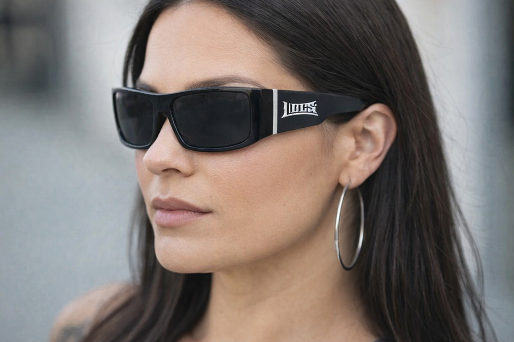 Woman wearing black sunglasses with a brand logo, against a blurred background