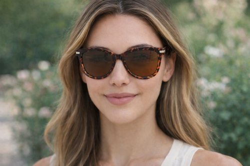 Woman wearing tortoise shell sunglasses with a blurred natural background